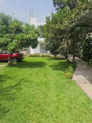 a yard with green grass and trees and a red car at CasaHotel Chaclacayo in Chaclacayo