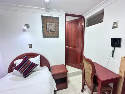 a bedroom with a bed and a desk and a chair at Libertrek in Cusco