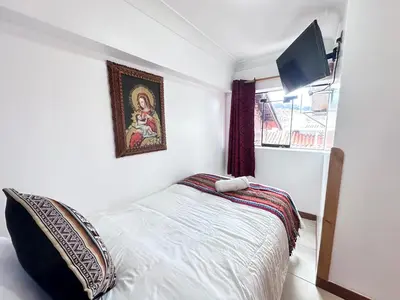 a bedroom with a bed and a tv on the wall at Libertrek in Cusco