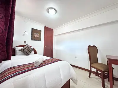a bedroom with a bed and a desk and a chair at Libertrek in Cusco