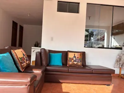 a living room with a brown leather couch with pillows at Viña J Felix in Lunahuaná