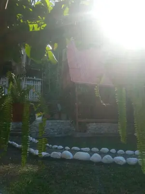 a garden with a house with the sun shining at Montañita Lodge in La Merced