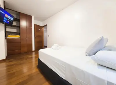 a bedroom with a white bed with a flat screen tv at E LarcomarZone Sea View All Inclusive 3B 701 in Lima