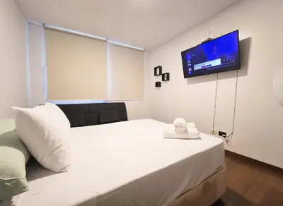 a bedroom with a white bed and a flat screen tv at E LarcomarZone Sea View All Inclusive 3B 701 in Lima