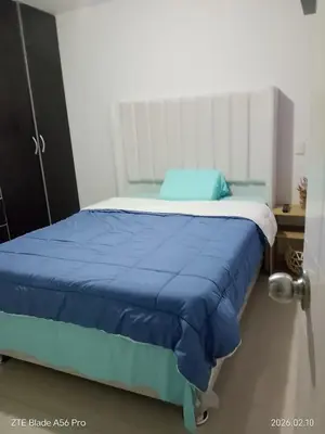 a bed in a bedroom with a blue blanket on it at Departamento 3 cuartos frente al mar en San Miguel, Peru in Lima