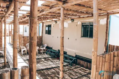 a room with wooden columns and tables and chairs at Bamboo Paracas Hotel in Paracas