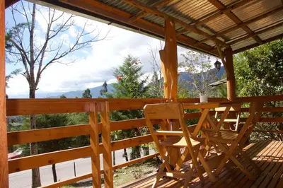 a wooden table and chairs on a deck at Cabaña con linda vista en Oxapampa in Oxapampa