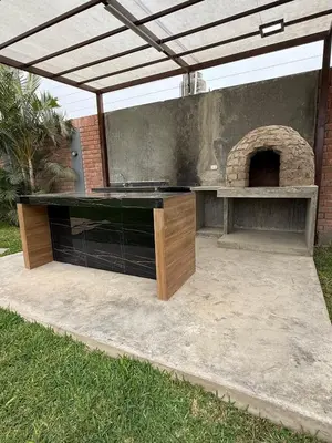 an outdoor grill with a table and an oven at Casa los Cipreses del Sol in Cieneguilla