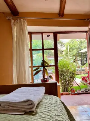 a bedroom with a bed and a window with a plant at La Huerta Refugio in Urubamba