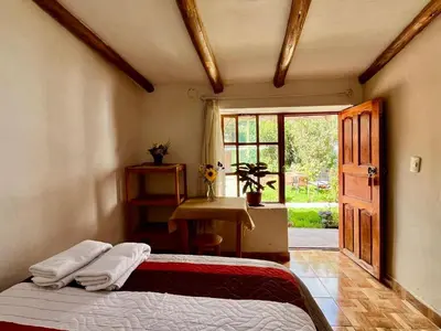 a bedroom with a bed and a door with a window at La Huerta Refugio in Urubamba
