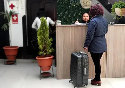 a woman waiting at a counter with her luggage at Ccapaq Wasi II in Cusco