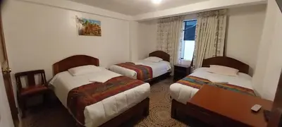 a hotel room with three beds and a window at Catari's House in Machu Picchu