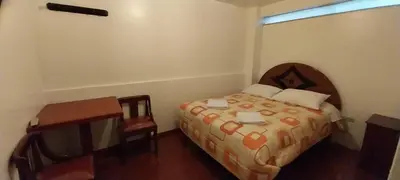 a bedroom with a bed and a desk and a window at Catari's House in Machu Picchu