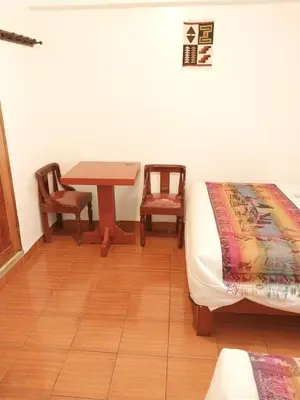 a room with a bed and a table and two chairs at Catari's House in Machu Picchu