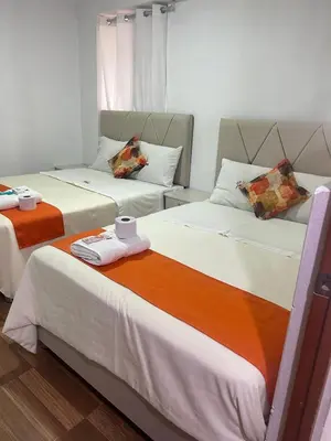 two beds in a hotel room with a cup and towels at Departamentos Sumaq Plaza II in Ayacucho