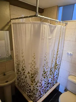 a bathroom with a shower curtain with a toilet and a sink at Nasca Travel One Hostel in Nazca