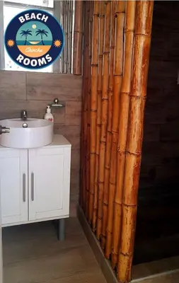 a bathroom with a bamboo shower curtain next to a sink at Beach Rooms Chincha in Tambo de Mora