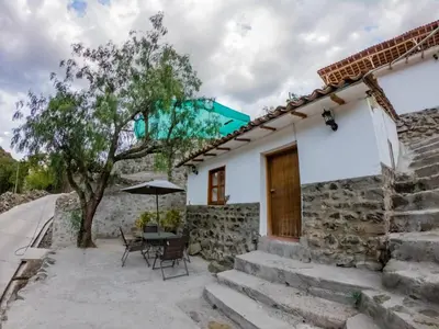 a house with a table and chairs and an umbrella at Kay Pacha Wellness Place Eco in Ayacucho