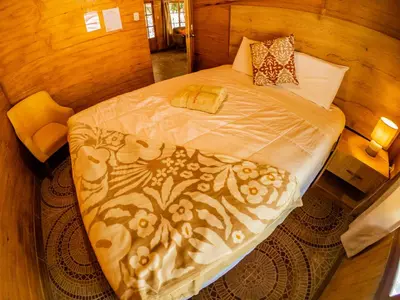 a large bed in a room with wooden walls at Kay Pacha Wellness Place Eco in Ayacucho