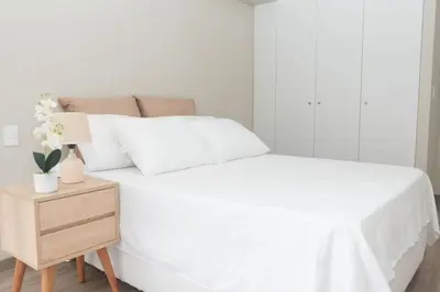 a bedroom with a white bed and a night stand at Estilo y comodidad in Lima
