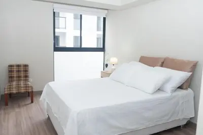 a white bed in a room with a window at Estilo y comodidad in Lima