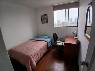 a bedroom with a bed and a desk and a window at Habitación acogedora amoblada in Lima