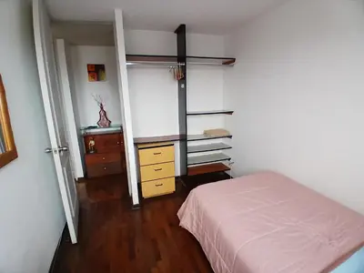a bedroom with a bed and a dresser and a shelf at Habitación acogedora amoblada in Lima