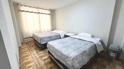 two beds in a small room with wooden floors at WIFI Rápido A 20 min del Aeropuerto de Lima in Lima