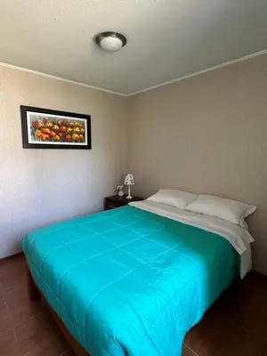 a bedroom with a blue bed with a picture on the wall at Casita en Ica con piscina in Ica