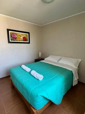 a bedroom with a large blue bed with two pillows at Casita en Ica con piscina in Ica