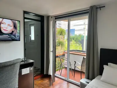 a room with a bed and a glass door with a balcony at La Casa del Viajero in Lima