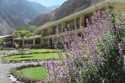 a building with purple flowers in front of it at Fundo Hotel Ayarpongo in Churín