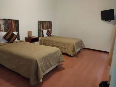 a hotel room with two beds and a flat screen tv at Fundo Hotel Ayarpongo in Churín