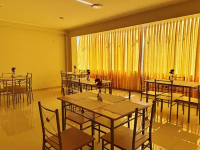 a dining room with tables and chairs with yellow curtains at Hotel AK7 in Nazca