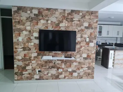 a television on a stone wall in a living room at Beautiful Complete Apartment in Lima