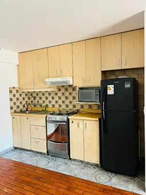 a kitchen with a black refrigerator and wooden cabinets at Monterrico Polo Aparts 6 - DPTO CON 3 CAMAS FRENTE EMBAJADA USA in Lima