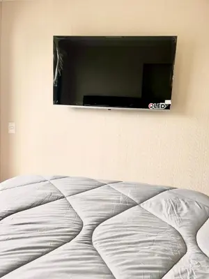 a bed in a room with a flat screen tv on the wall at Tu refugio en Lima, moderno y céntrico in Lima