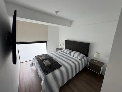 a white bedroom with a bed and a window at Premium apartment in Miraflores with rooftop pool in Lima