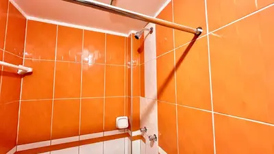 a bathroom with orange tiled walls and a shower at Habitación privada a 20 min del aeropuerto de Lima in Lima