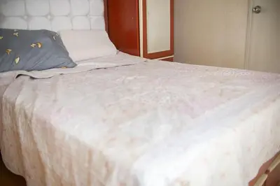 a large white bed with a blue pillow on it at Hermoso apartamento cerca al estadio San Marcos y el Aeropuerto in Lima