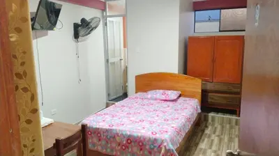 a small bedroom with a bed with a pink comforter at Hospedaje El Sureño in Satipo