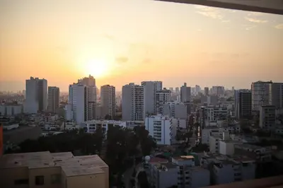 a city skyline with the sun setting behind buildings at Brand new apartment in Olivar of San Felipe in Lima