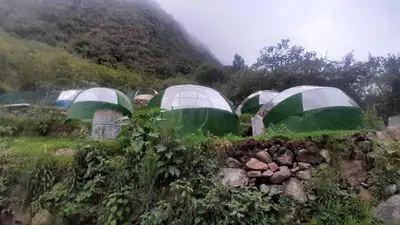 a group of green and white tents on a hill at Chaullay Star Domes in Colcapampa