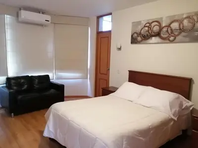 a bedroom with a white bed and a black chair at Belle Sand Hotel in Ica