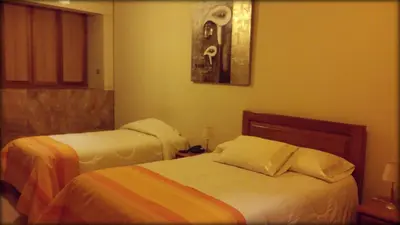 a hotel room with two beds and a picture on the wall at Belle Sand Hotel in Ica