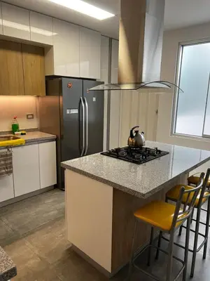 a kitchen with a island with a stove and a refrigerator at Amplio y acogedor departamento de 130m2 - 2do piso in Lima