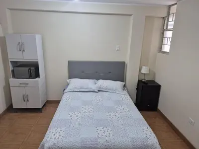 a small bedroom with a bed and a microwave at Habitación privada 2do piso cerca a la Plaza Constitución in Huancayo