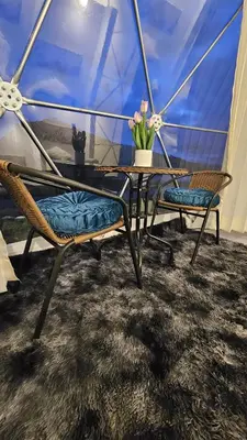 a table with two chairs and a vase with flowers on it at Sky domos - laguna huaypo in Anta