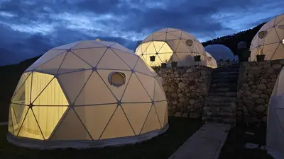 three geodesic domes are lit up at night at Sky domos - laguna huaypo in Anta