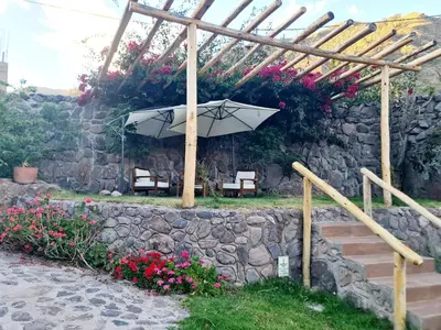 a stone wall with an umbrella and some flowers at Arins House in Cusco